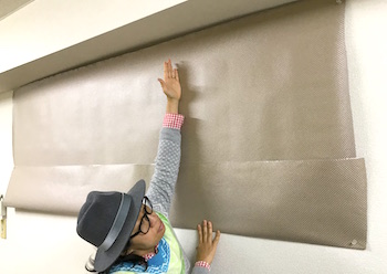 事務所の壁に実寸大の紙を貼ってサイズを確認する様子